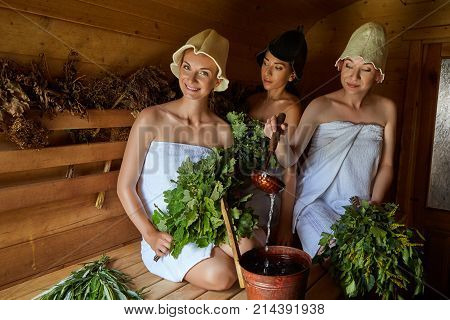three beautiful young women in towels realxing in wooden sauna. inside shot with natural light.