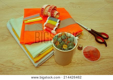 Sewing tools and sewing kit on wooden textured background. Sewing kit. Thread needles and cloth. tailor workspace with sewing and handmade tools