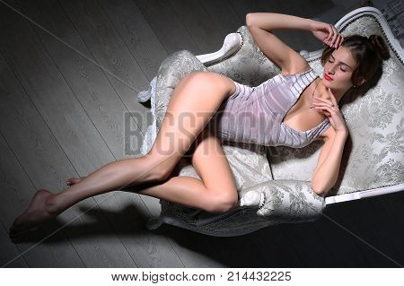 Sexy young model chilling in a classic couch. Studio shot.