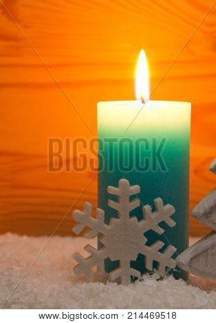 Avent candle and snowflake isolated on wood background. Christmas background with blue candle and white snowflake.