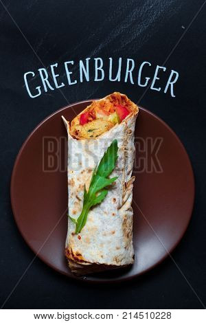 Nice and ready to eat shaurma or sandwich with cut in half tomatoes nearby, topview greenburger