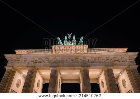 Historic Brandenburg Gate and four horses bronze statue illuminated at night against dark black sky