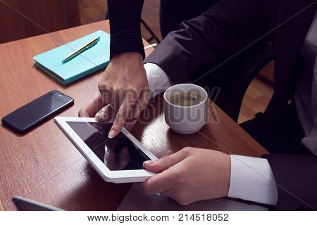 Collaboration in business office. Women's finger specifies in the tablet