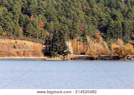 View of a mountain lake, a forest and a small church on a sunny autumn day (Greece, mountainous Corinthia)