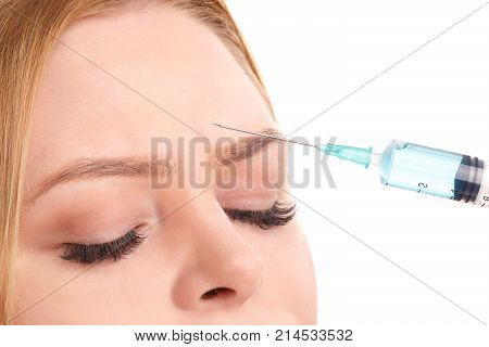 A syringe with an injection near the forehead of a young and attractive woman. Isolated on white background.