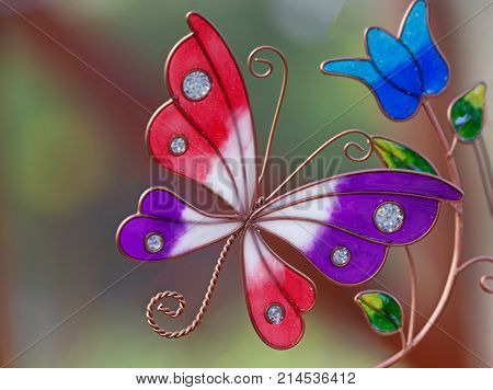 Beautiful pink purpe and white glass butterfly and blue fower with green leaves wtih a blurred background and space for text.