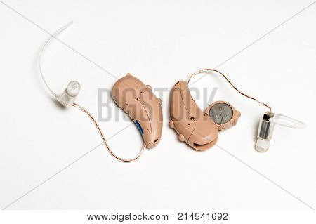 Macro close up of a matched pair of tiny modern hearing aid showing battery on white isolated background