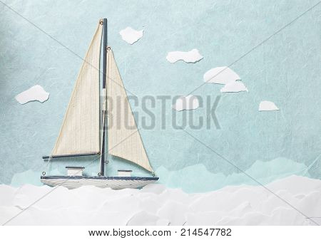 Toy sailboat on blue background from paper with cloud made of paper.