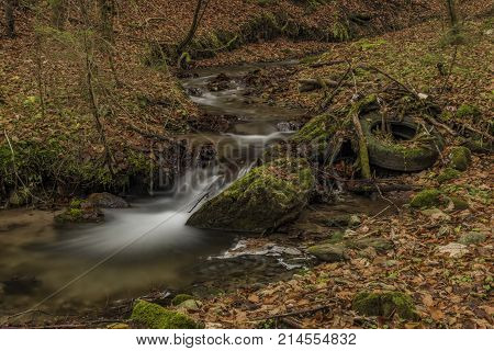 Dirty Bansky creek near Spania Dolina village near Banska Bystrica city with old rubber wheel
