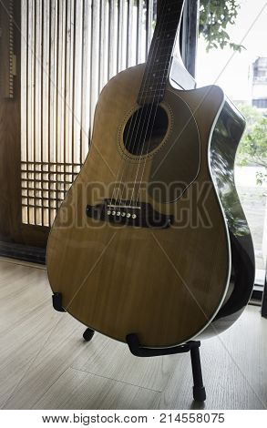 Acoustic guitar resting against mirror background stock photo