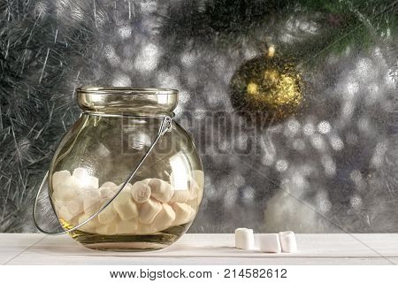 Marshmallows in a decorative jar on the sill of the frosted window.
