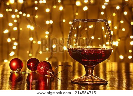 Christmas colorful balls and glass cognac or whiskey with defocused lights.