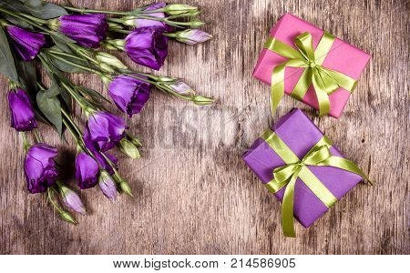 Bright gift boxes with ribbons and purple flowers. A bouquet of eustoms and a romantic gift