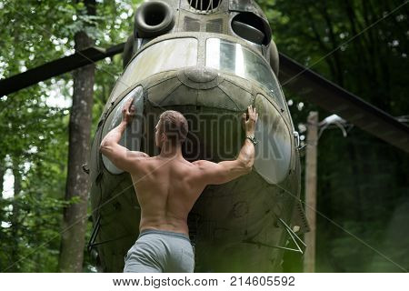 Travelling discovery adventure. Man athlete push helicopter in forest. Goal achievement success. Bodybuilder with muscular torso at heli aircraft. Power energy strength concept.