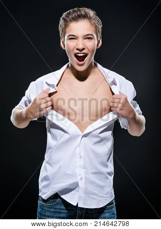 Photo of guy at the age of a teenager tearing shirt on chest. Teen boy screeming 