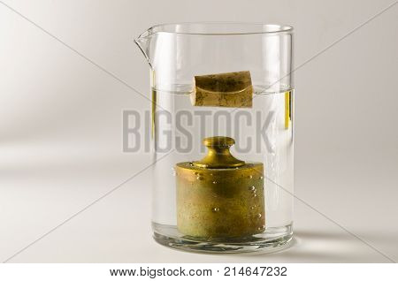 Physics. A cork floats in water and a antique weight sinks. 