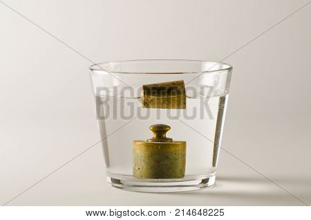 Physics. A cork floats in water and a antique weight sinks.