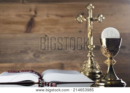 Catholic concept background. Golden chalice, rosary and Holy Bible.