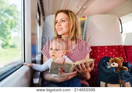 Young mother travelling with baby boy by train. Railway journey of a beautiful woman and her son.