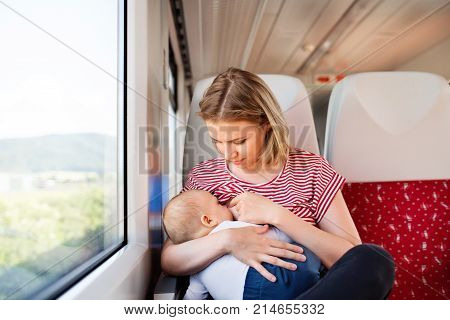 Young mother travelling with baby boy by train. Railway journey of a beautiful woman and her son.