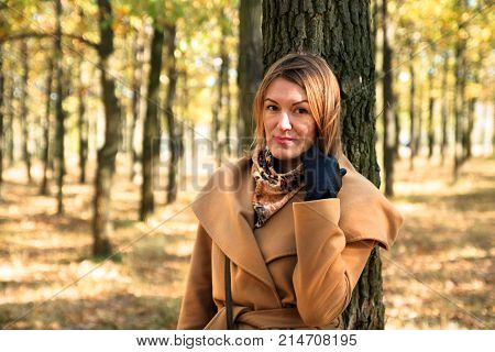nice woan stand near the tree in the park. Autun yellow and orange leafs