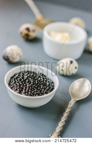 A black caviar in a white ceramic bowl.