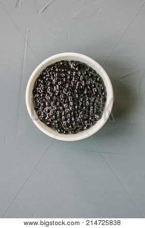 Top view of black caviar in white ceramic bowl