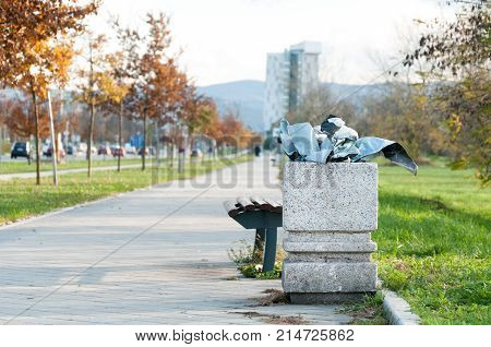 Garbage in the city. Concrete garbage can full of litter on the urban street in the city