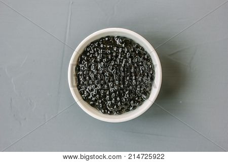 Top view of black caviar in white ceramic bowl