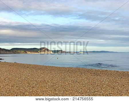 Beautiful coast in Lyme Regis in Dorset United Kingdom. Pebble beach with sea and cliffs in the background with a moody sky and space for text.