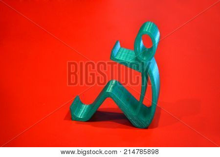 Abstract isolated object of a green color printed on a 3d printer on red surface. Fused deposition modeling, FDM. Progressive modern additive technology. Concept of 4.0 industrial revolution