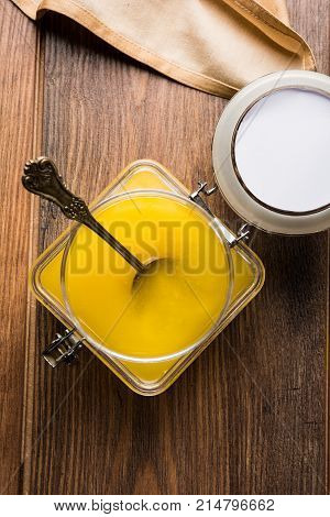 Desi Ghee or clarified butter in glass or Copper container or ceramic jar with spoon, selective focus