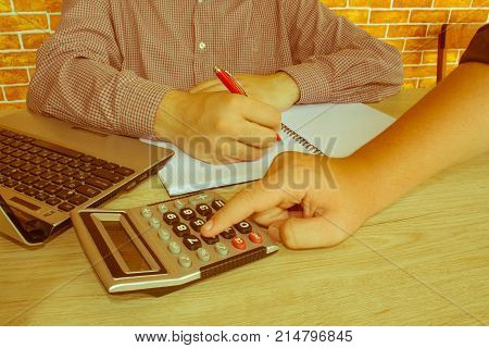 Business people are using calculator to work. Young Business people Calculating Finance Bills In Office - Retro color