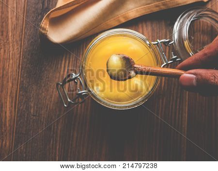 Desi Ghee or clarified butter in glass or Copper container or ceramic jar with spoon, selective focus