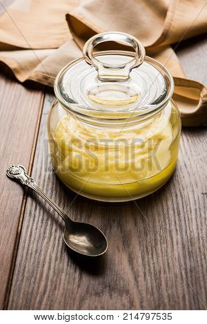 Desi Ghee or clarified butter in glass or Copper container or ceramic jar with spoon, selective focus