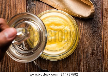 Desi Ghee or clarified butter in glass or Copper container or ceramic jar with spoon, selective focus