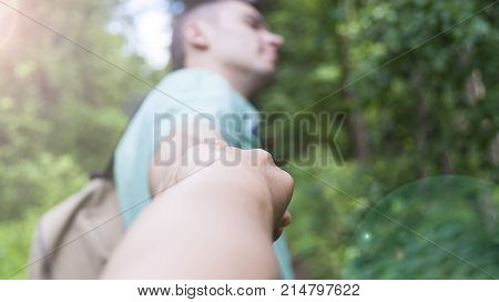 The young man pulls the girl's hand on the forest path