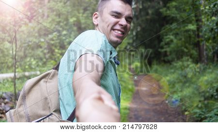 The young man pulls the girl's hand on the forest path