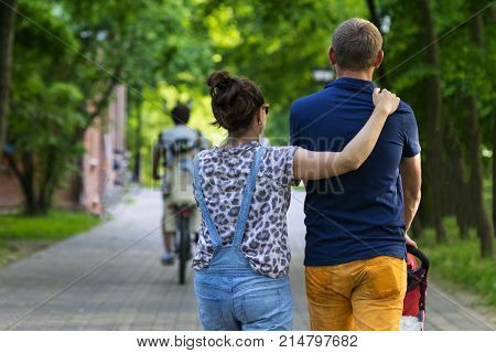 Young couple walking with child in the Park. Summer.