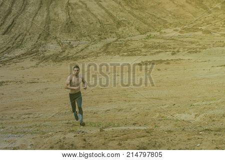 The young man is wearing sweatpants in the desert