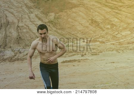 The young man is wearing sweatpants in the desert