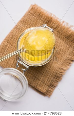 Desi Ghee or clarified butter in glass or Copper container or ceramic jar with spoon, selective focus
