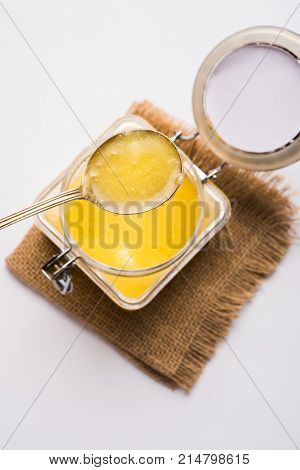 Desi Ghee or clarified butter in glass or Copper container or ceramic jar with spoon, selective focus