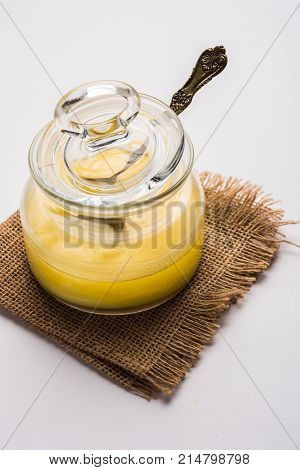 Desi Ghee or clarified butter in glass or Copper container or ceramic jar with spoon, selective focus