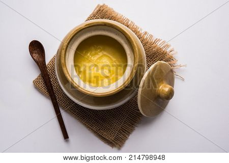 Desi Ghee or clarified butter in glass or Copper container or ceramic jar with spoon, selective focus