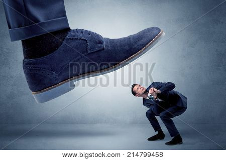 Big foot trying to crush small man who is afraid of that