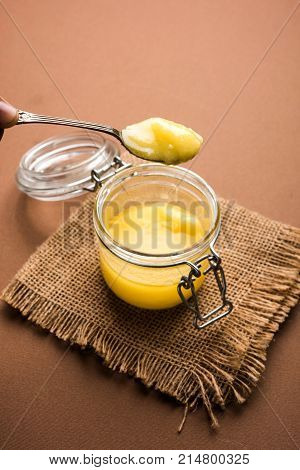 Desi Ghee or clarified butter in glass or Copper container or ceramic jar with spoon, selective focus