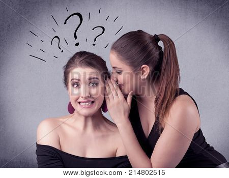 A teenager girl looking confused with drawn question marks above the head, while a girlfriend whispers something in her ear concept.