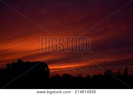 Dramatic and bright sunset. Dark ground. Orange clouds