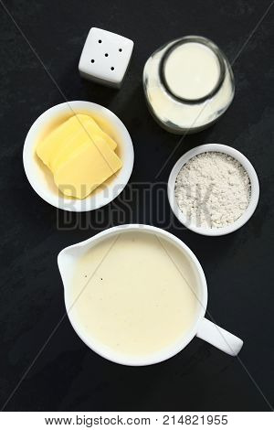 Homemade French Bechamel or White Sauce served in sauce boat with ingredients on the side (flour butter milk) photographed overhead on slate with natural light (Selective Focus Focus on the sauce)